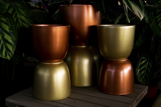 Conjunto de maceteros de metal opaco de color dorado y rojizo.
