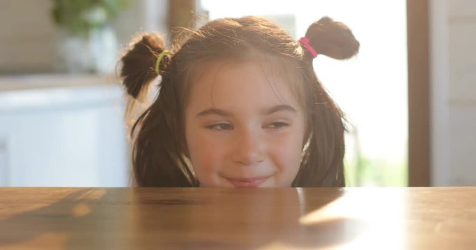 Little cute girl on kitchen. Charming little girl on kitchen is looking from under the table