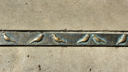 Серая стена со стальной полосой украшенной орнаментом из птиц