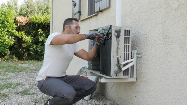 handsome young man electrician installing air conditioning in a client house

