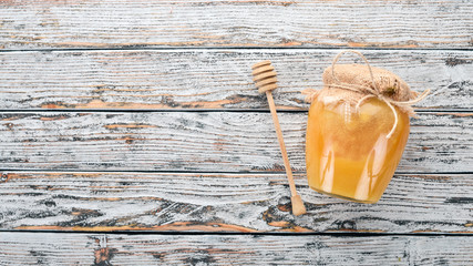 Honey in a jar on a white wooden background. Free space for text. Top view.