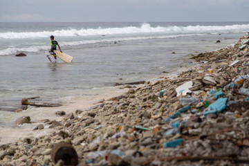 Kid surfing on beach with lots of waste I