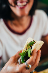 Happy young woman eating street tacos at outdoor mexican restaurant. Mexican food.