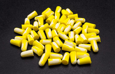 A lot of lying earplugs, for protection against noise in yellow and white, isolated on a black...