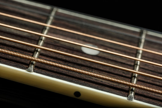 Wooden frets and bronze strings of acoustic guitar on black background. Blues and Rock wallpaper