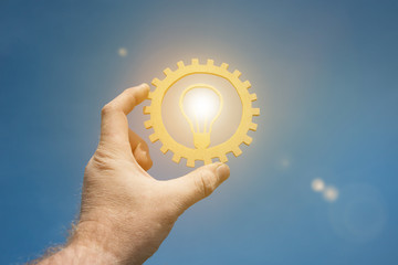 A burning lamp is an idea in the businessman's hand, against the sky. Business concept, innovation,...