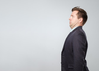 Side view portrait of mature man in suit with double chin looking with some fear on face.
