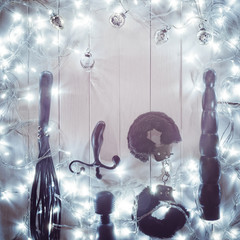 Christmas composition made of various sex toys is on a white wooden background. Around the toys is...