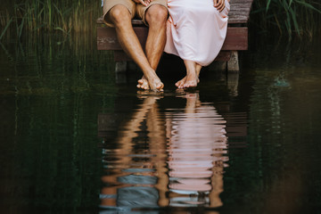Spiegelung der Füße und Beine eines Liebespaars im Wasser eines Sees