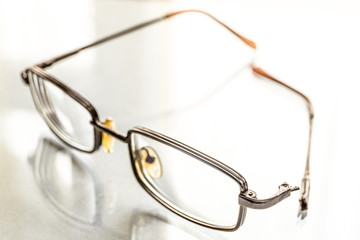 Eyeglasses with a broken handle on a bright background. Limited depth of field.