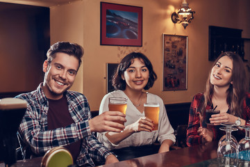 Group of young multiracial smiling people resting in the pub.