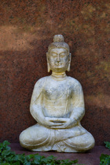 Sitzender Buddha vor einer roten Marmorplatte