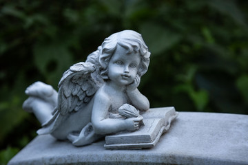 Ein Engel liegt auf dem Bauch und schreibt in ein Buch