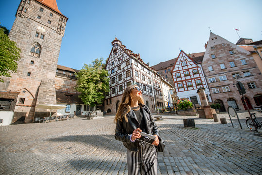 Portrait of a young woman tourist standing on the beautiful city square with old buildings, traveling in Nurnberg, Germany