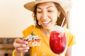 Young woman enjoying tasty traditional spanish snack tapas, with glass of sangria wine. Travel and Food in Spain concept