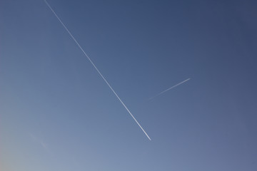 Plane flying on a blue sky, condensation line.