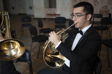 French horn player. Hornist playing brass orchestra music instrument.