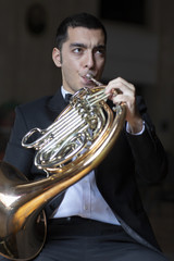 French horn player. Hornist playing brass orchestra music instrument.