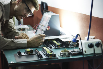 Engineer soldering circuit board in office