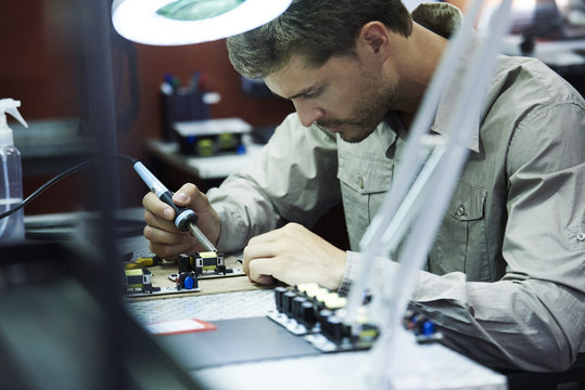 Engineer soldering circuit board in office