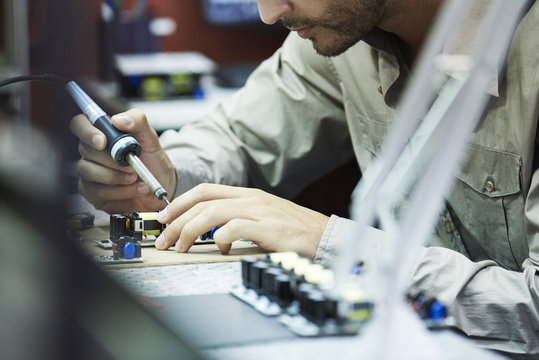 Engineer soldering circuit board in office