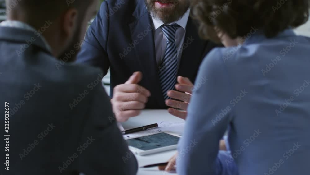 Poster tilt up shot of middle aged man using tablet computer to show apartment blueprint to clients or coll