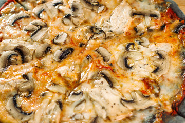 Pizza with champignons and chicken breast on black dough.