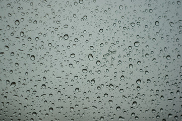raindrops on window glass on background of cloudy sky