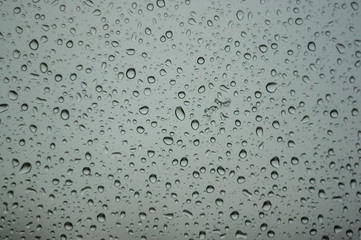 raindrops on window glass on background of cloudy sky