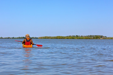 Man paddles a yellow kayak on Danube river. Summer kayaking