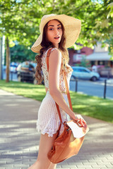 Sunny lifestyle fashion portrait of young stylish hipster woman walking on the street, wearing trendy outfit, straw hat, travel with backpack.