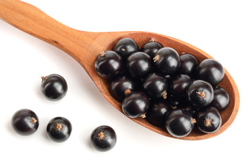 black currant in wooden spoon isolated on white background. Top view. Flat lay pattern