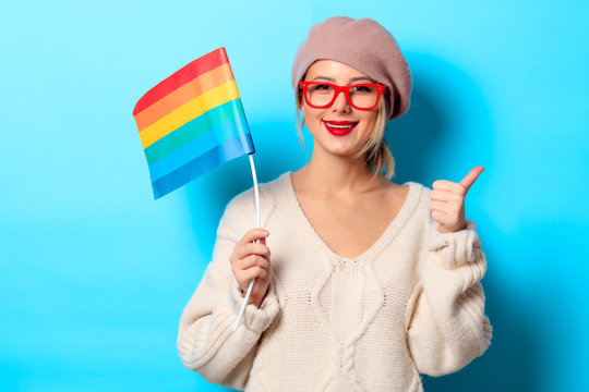 Portrait of a young girl in white sweater with LGBT flag on blue background