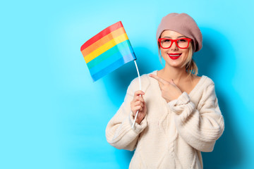 Portrait of a young girl in white sweater with LGBT flag on blue background