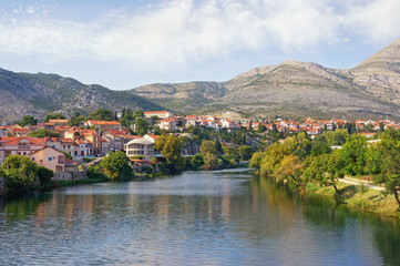 Fototapeta na wymiar Picturesque landscape with town on river bank. Bosnia and Herzegovina, Republika Srpska. View of Trebisnjica river and Trebinje town, autumn