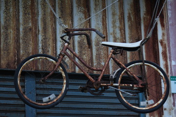 Fototapeta na wymiar Old rusty bike as vintage design and decoration infront of corrugated metal house on Cijin Qijin Island, Kaohsiung City, Taiwan 