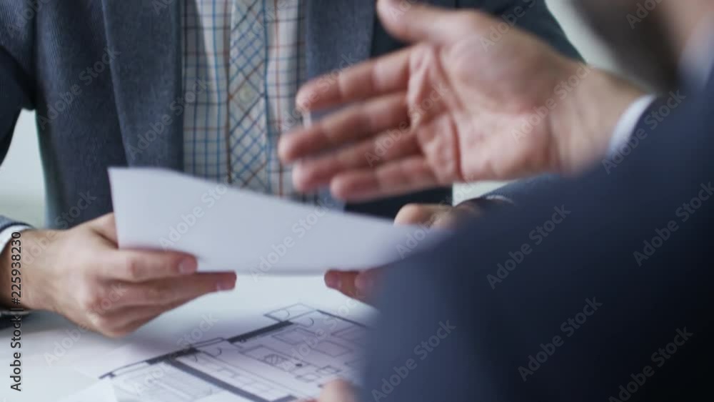 Poster tilt up shot of unrecognizable real estate agent giving terms and conditions document to male client