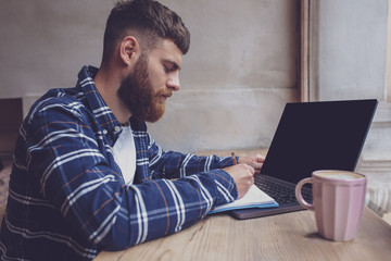 Young man chatting via net-book during work break in coffee shop