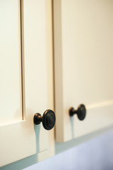 Detail view of new, professionally installed cupboards with black knobs.  Vertical image with shallow depth of field.