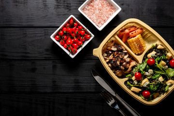 Salad and chicken strips with caramelized onions and almonds. Carrot and corn. Brazilian lunch box. top view