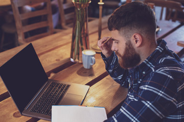 Young man chatting via net-book during work break in coffee shop