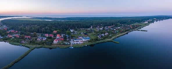 Fototapeta premium Beautiful sunset over estuary of Vistula river in Gdansk. Summer sunset over sea and river and small village.