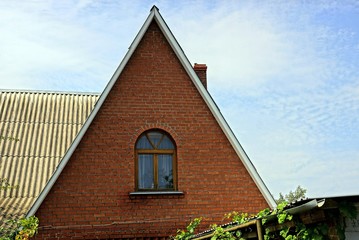 facade of the house of brick brown attic with a window against the sky