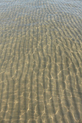 Fototapeta na wymiar texture d'acqua su sfondo di sabbia nel Mare Adriatico