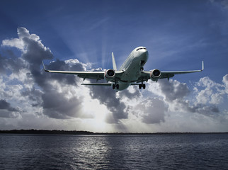 Fototapeta na wymiar Jet Airliner Flying in subeams and cumulonimbus cloudy sky.