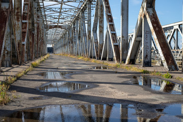 Old railway bridge with pedestrian barriers. Railway bridge over the river.