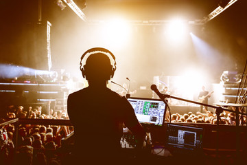 DJ with crowd of people in night club party under stage light.