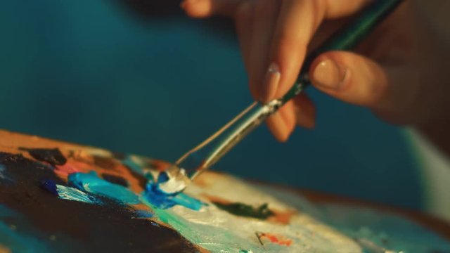 Female artist mixing paints on palette with brush. Close up woman hand holding paintbrush. Education in art school