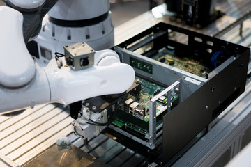 Robotic arm installing a computer chip in factory. Industrial and factory with machine technology 4.0 concept.