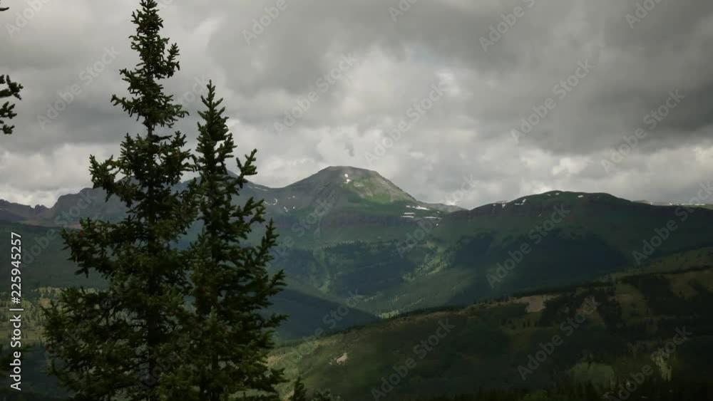 Aufkleber time lapse of a mountain top with clouds moving above. trees in foreground with mountain in the back